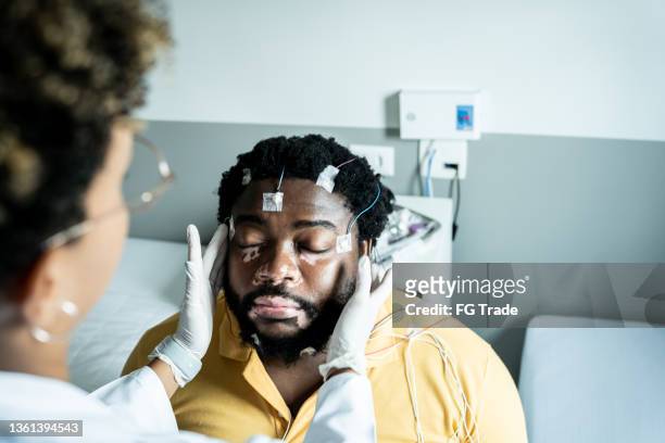 doctor placing electrodes on patient's head for a polysomnography (sleep study) - neurosurgery stock pictures, royalty-free photos & images
