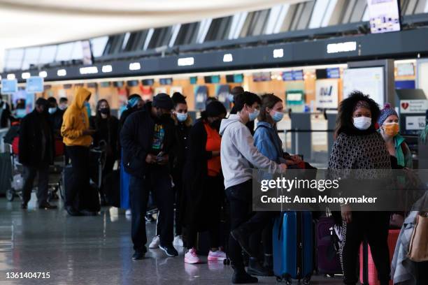 Passengers wait in line to check in for their flights at the Dulles International Airport on December 27, 2021 in Dulles, Virginia. According to...