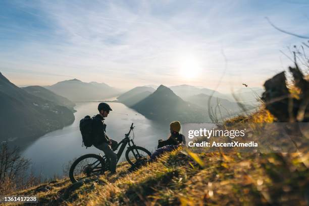 mountain bikers relax on grassy mountain ridge - ticino stockfoto's en -beelden