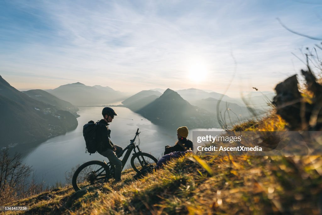 Mountain bikers relax on grassy mountain ridge