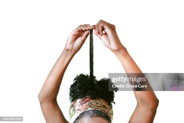 black woman with kinky/coily natural hair pulls on section of hair - natürliches haar stock-fotos und bilder