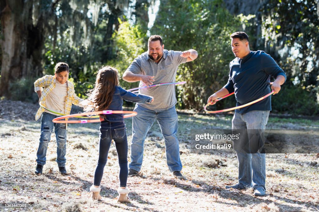 Hispanic fathers and children at park playing with hoops