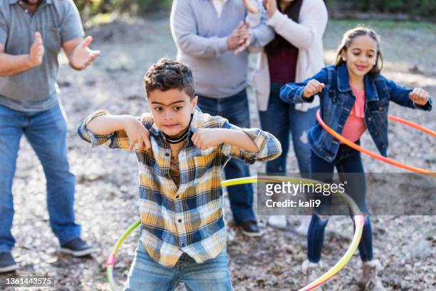 two hispanic children hooping while family watches - hooping stock pictures, royalty-free photos & images