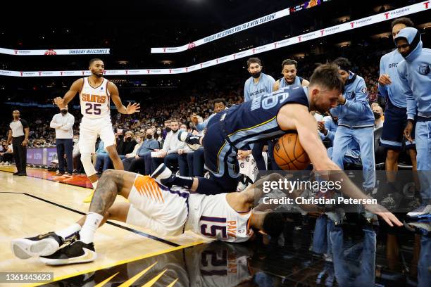 John Konchar of the Memphis Grizzlies and Cameron Payne of the Phoenix Suns collide as they attempt to save an out-of-bounds ball during the first...