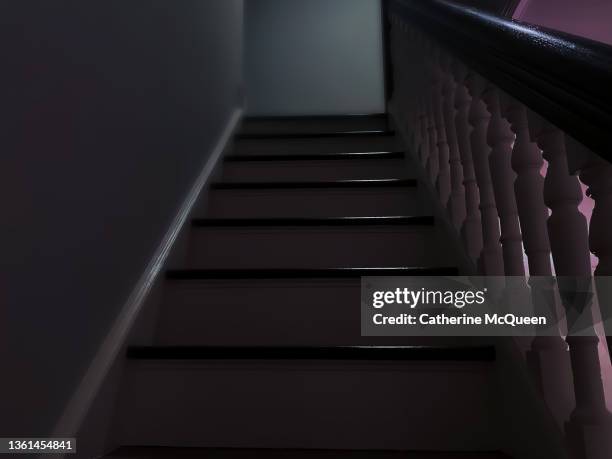 haunting view from bottom of stairs of dark upstairs corridor - creepy house at night stock-fotos und bilder