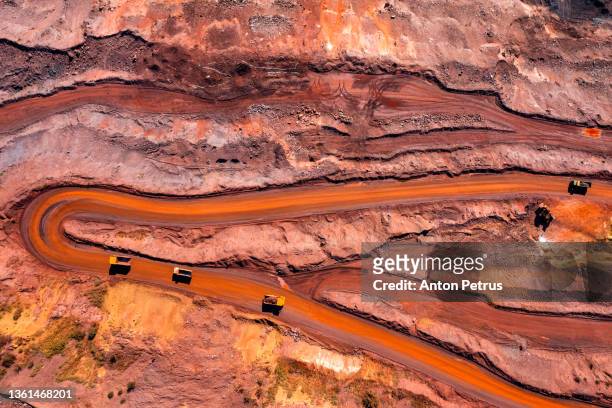 aerial view of open pit iron ore and heavy mining equipment. - mijnindustrie stockfoto's en -beelden