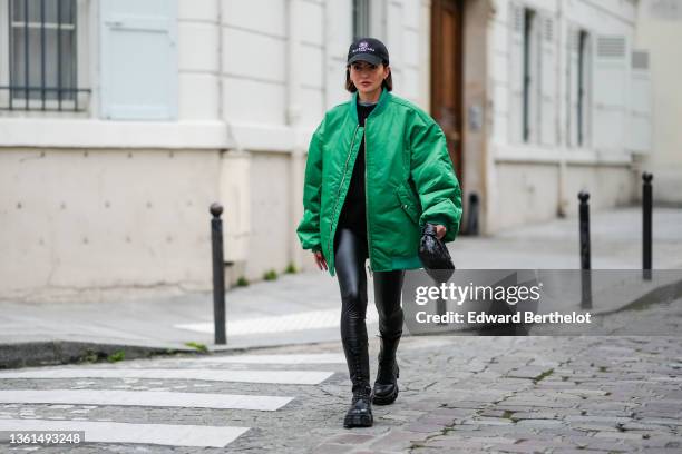 Alexandra Pereira wears a black cap with white inscriptions and logo from Balanciaga, silver and gold earrings, a white t-shirt, a black ribbed wool...