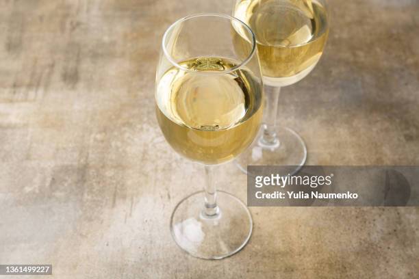 two glasses of white wine. wine glasses over a brown background - trying new food stock pictures, royalty-free photos & images
