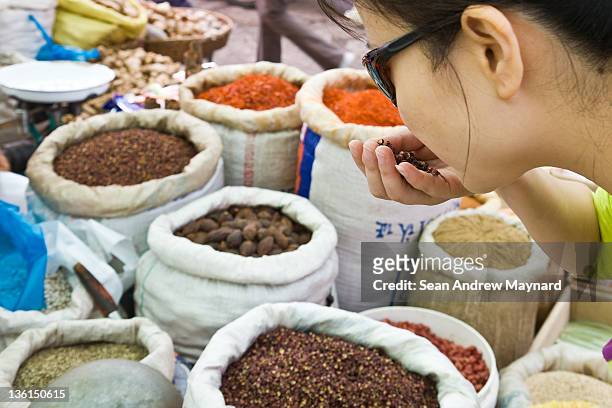 woman smelling spices at market - smelling spices at food market stockfoto's en -beelden