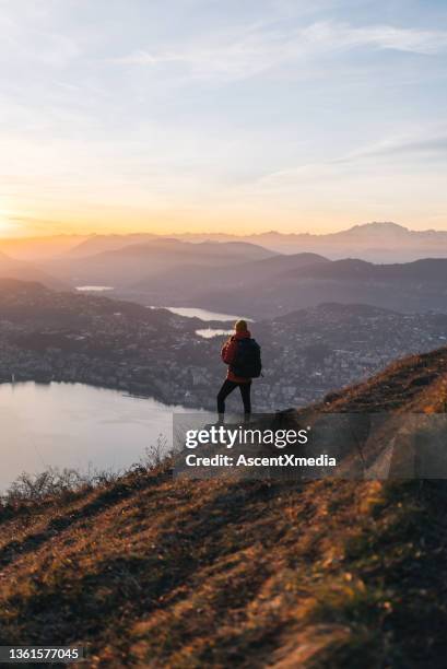 wanderfrau entspannt sich bei sonnenaufgang auf grasbewachsenem bergrücken - lugano stock-fotos und bilder