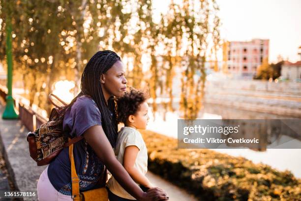 black mother and daughter looking at the city river - park family sunset stock pictures, royalty-free photos & images