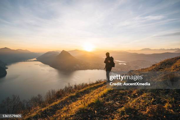 caminhante fêmea segue trilha ao longo da cordilheira da montanha ao nascer do sol - lugano - fotografias e filmes do acervo