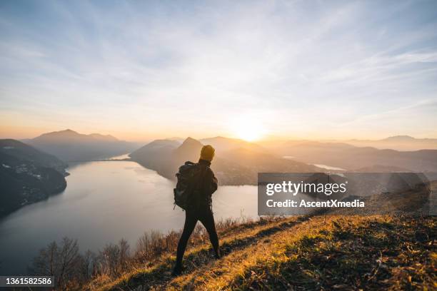 female hiker follows trail along grasy mountain ridge at sunrise - lugano switzerland stock pictures, royalty-free photos & images