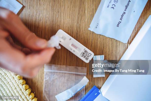 a woman using covid-19 rapid self-test kit at home - corona virus stock-fotos und bilder