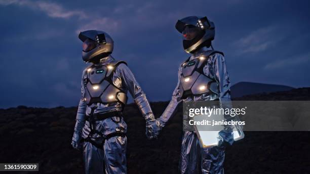 selfie out of this world. astronauts in futuristic, illuminated suits holding hands and taking a photo - cosplayer stock pictures, royalty-free photos & images