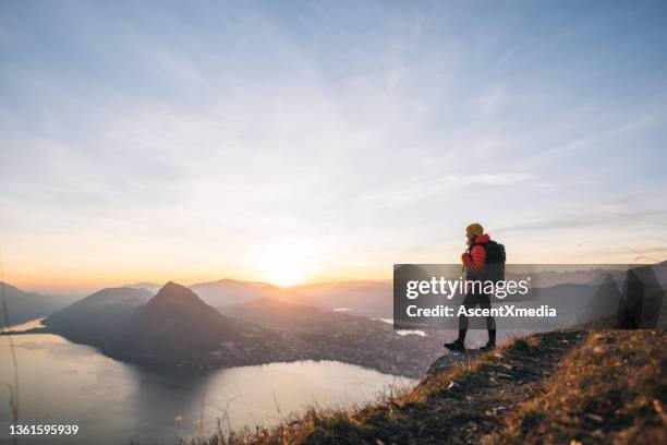 female hiker relaxes on grassy mountain ridge at sunrise - padded jacket 個照片及圖片檔