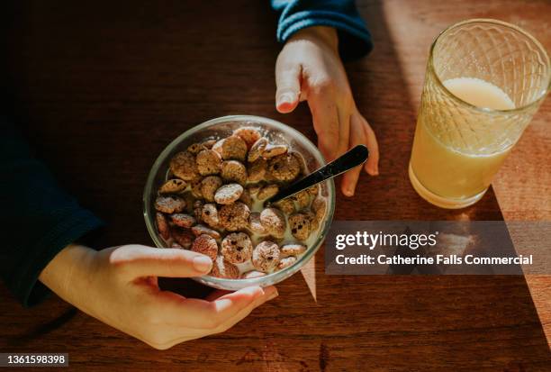 top down image of a child eating a small bowl of breakfast cereal - orange juice small stock pictures, royalty-free photos & images