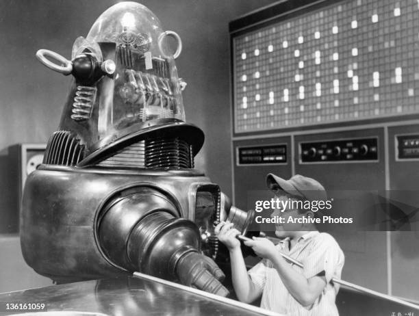 Richard Eyer hooks Robby the Robot up to a computer in a scene from the film 'The Invisible Boy', 1957.