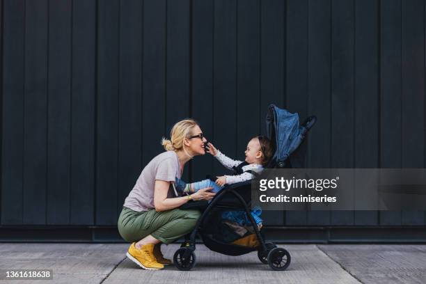 mother and daughter playing outside - kinderwagen stockfoto's en -beelden