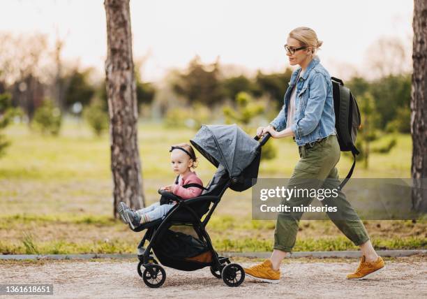 mother and daughter: a walk in the park - kinderwagen stockfoto's en -beelden