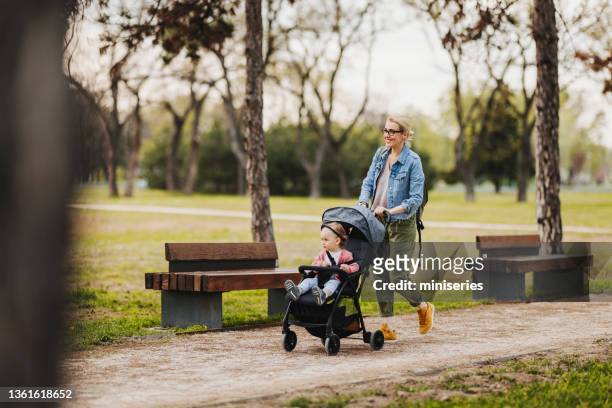 mother and daughter: a walk in the park - baby pram in the park stock pictures, royalty-free photos & images