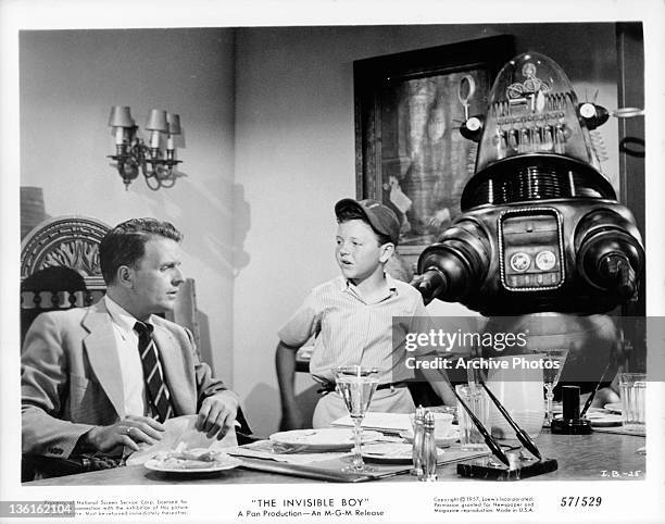 Richard Eyer and Robby the Robot come to see Philip Abbott at the dining table in a scene from the film 'The Invisible Boy', 1957.