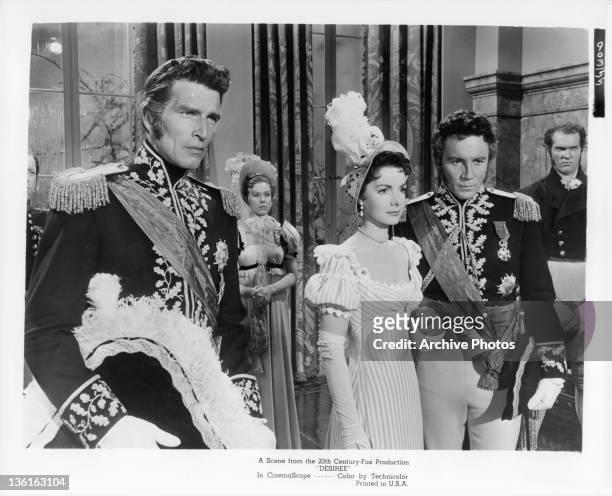 Michael Rennie stands near as Elizabeth Sellars holds the hand of unidentified actor in a scene from the film 'Desiree', 1954.