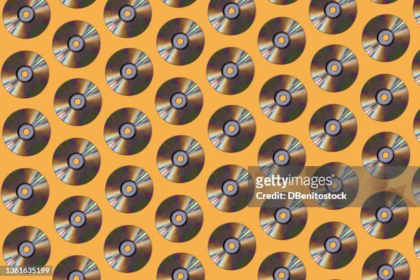 silver compact discs pattern on yellow background. music, storage, dating and retro vintage concept. - musica pop foto e immagini stock