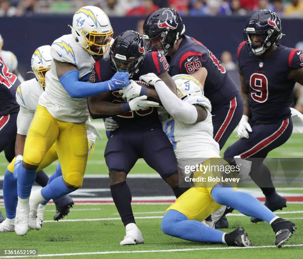 Royce Freeman of the Houston Texans is tackled by Kyzir White of the Los Angeles Chargers and Kenneth Murray at NRG Stadium on December 26, 2021 in...