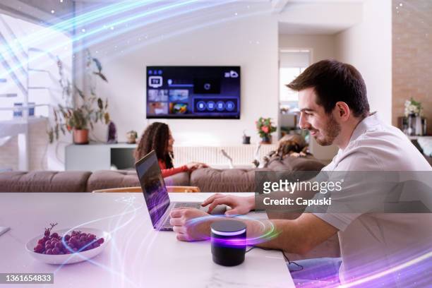 couple using smart speaker while doing other everyday tasks - domotic bildbanksfoton och bilder