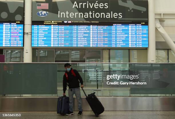 Traveler stands under the arrivals board at Pearson International Airport on December 27 in Toronto, Canada.