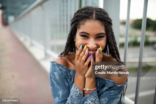 silly teenager sniggering while facing camera directly - multi coloured nails stock pictures, royalty-free photos & images
