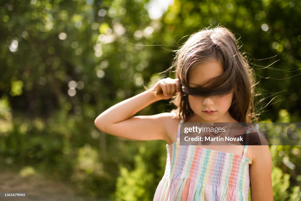 Ashamed child covering her eyes with hair