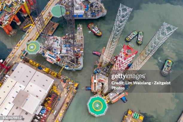 aerial shot of oil rig leaving shipyard - shipyard aerial stock pictures, royalty-free photos & images