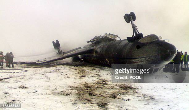 Rescuers work near an overturned Russian-made Tupolev 134 passenger jet at the airfield outside Osh on December 28, 2011. The packed TU-134 flipped...
