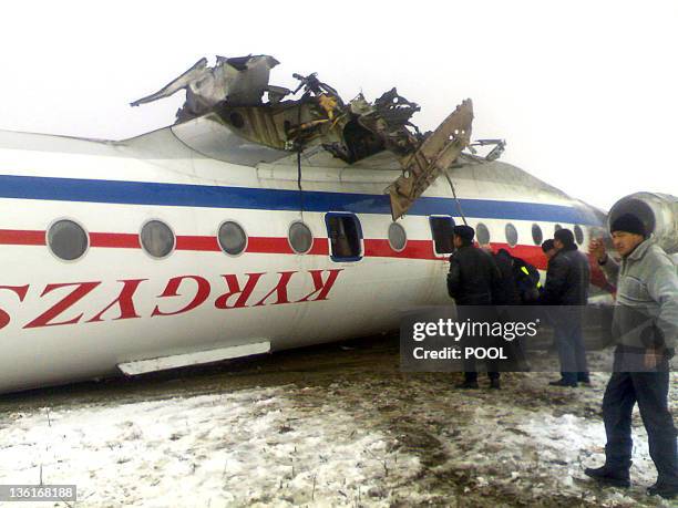 Rescuers work near an overturned Russian-made Tupolev 134 passenger jet at the airfield outside Osh on December 28, 2011. The packed TU-134 flipped...