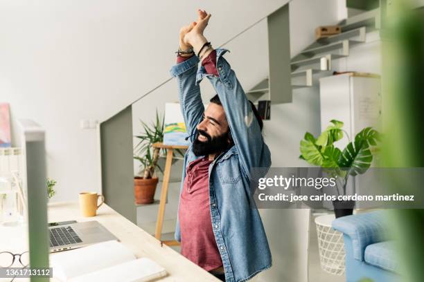tired man stretches after working with computer - strekken stockfoto's en -beelden