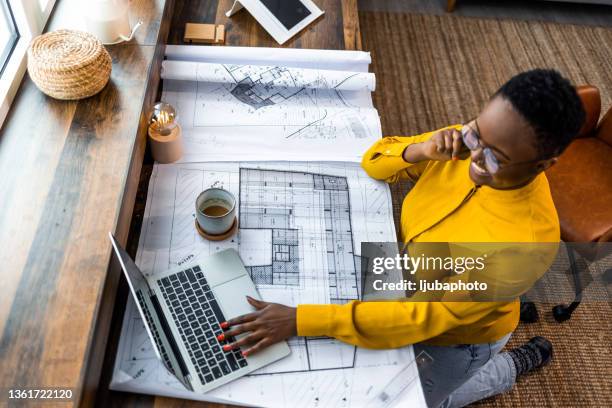 black female architect studying plans in open plan - yellow shirt stock pictures, royalty-free photos & images