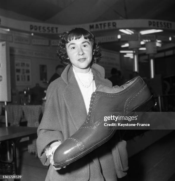Une femme présente une chaussure géante lors de la semaine du cuir au Parc des expositions de Versailles, le 14 septembre 1951.