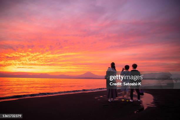 vue arrière de trois personnes regardant le mont fuji depuis la plage de shonan au coucher du soleil - femme de dos smartphone photos et images de collection