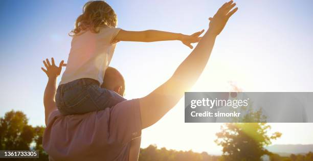 father carrying his daughter on the shoulder outdoors - carrying on shoulders stock pictures, royalty-free photos & images