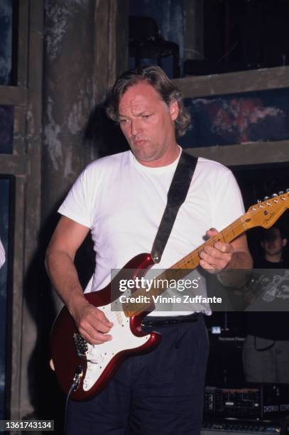 British guitarist David Gilmour, wearing a white t-shirt, plays his candy apple red Fender Stratocaster 57V, circa 1988. Gilmour is possibly shown...