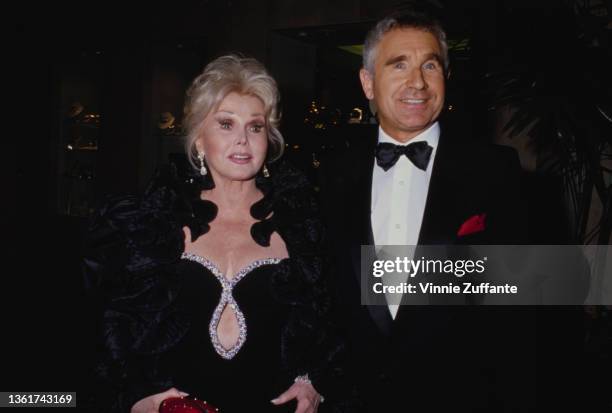 Hungarian-American actress and socialite Zsa Zsa Gabor , wearing a black evening dress with a keyhole neckline trimmed with silver, and her husband,...