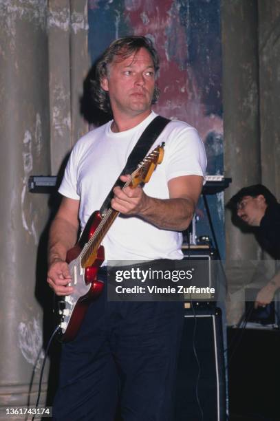 British guitarist David Gilmour, wearing a white t-shirt, plays his candy apple red Fender Stratocaster 57V, circa 1988. Gilmour is possibly shown...