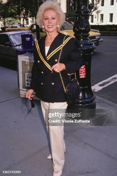 Hungarian-American actress and socialite Eva Gabor , wearing a naval-style double-breasted jacket with gold detail, and pink, white and blue striped...