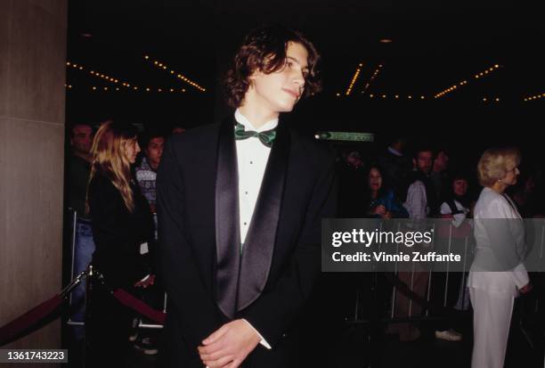 American actor and singer Jason Gould wearing a black tuxedo with a green bow tie, attending an event at the Cineplex Odeon Theater on Century Plaza...