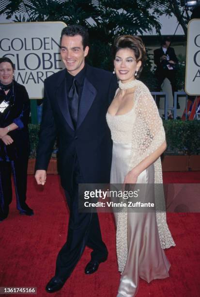 American actor Jon Tenney, wearing a black tuxedo with a black shirt and black tie, and his wife, American actress Teri Hatcher, wearing a silver...