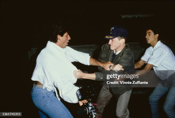 American actor Sean Penn, wearing a green jacket and a baseball cap, is restrained by a man as fights with a photographer Anthony Savignano outside...