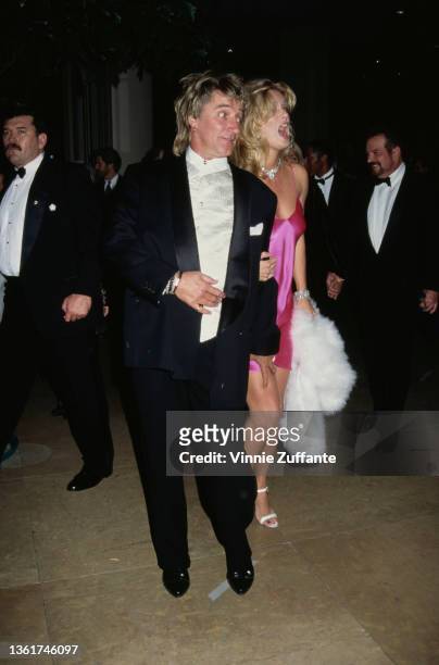British singer and songwriter Rod Stewart, and his wife, New Zealand model Rachel Hunter, wearing a pink dress, attend the 10th Carousel of Hope...