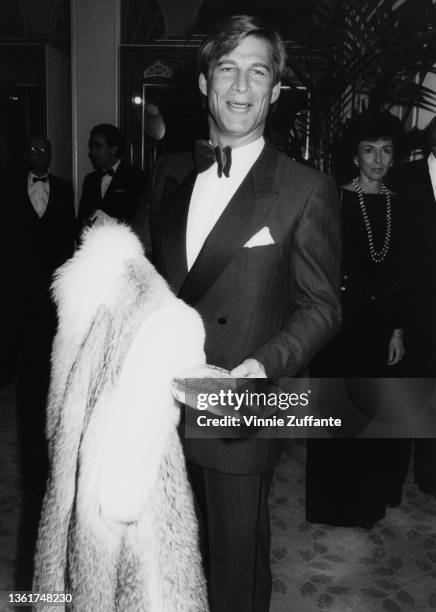British actor Simon MacCorkindale , wearing a tuxedo, and holding his partner's fur coat, attends the 12th Annual People's Choice Awards, held at the...